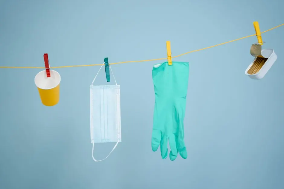 Various recyclable items like glove, mask, and can hanging on a clothesline.